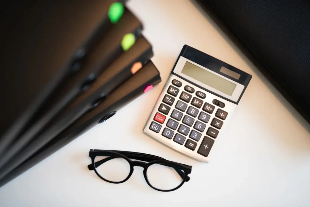 Calculadora, lápis e caderno sobre uma mesa