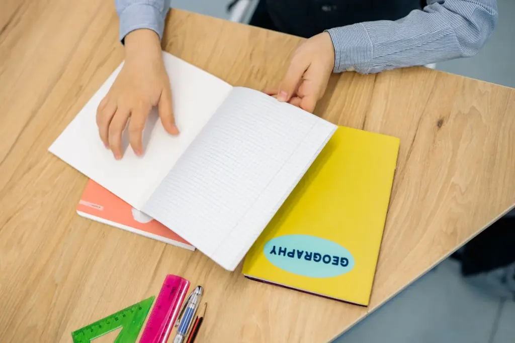 Estudante escrevendo em um caderno sobre a mesa